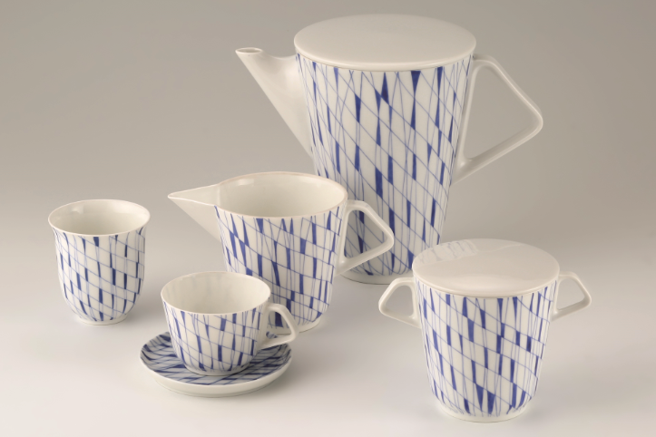 Das Foto zeigt ein Porzellan-Mokka-Service in weiß-blauem Rautendekor mit Kaffeekanne, Mokkatasse mit Untertasse, Zuckerdose, Milchkännchen und Becher