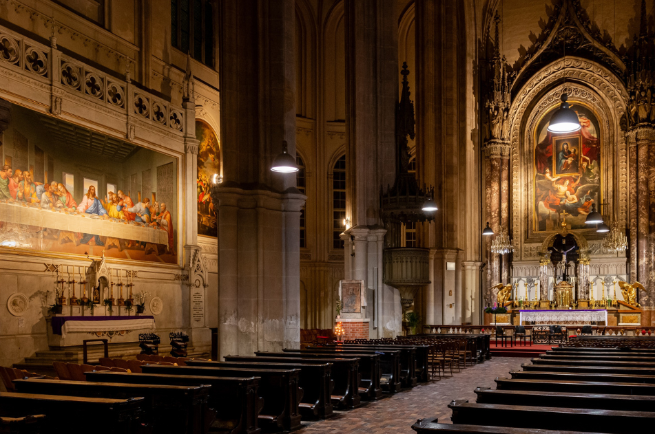 The photo shows the interior of the Minorite Church with the high altar and the mosaic "The Last Supper" after Leonardo Da Vinci, all in solemn lighting