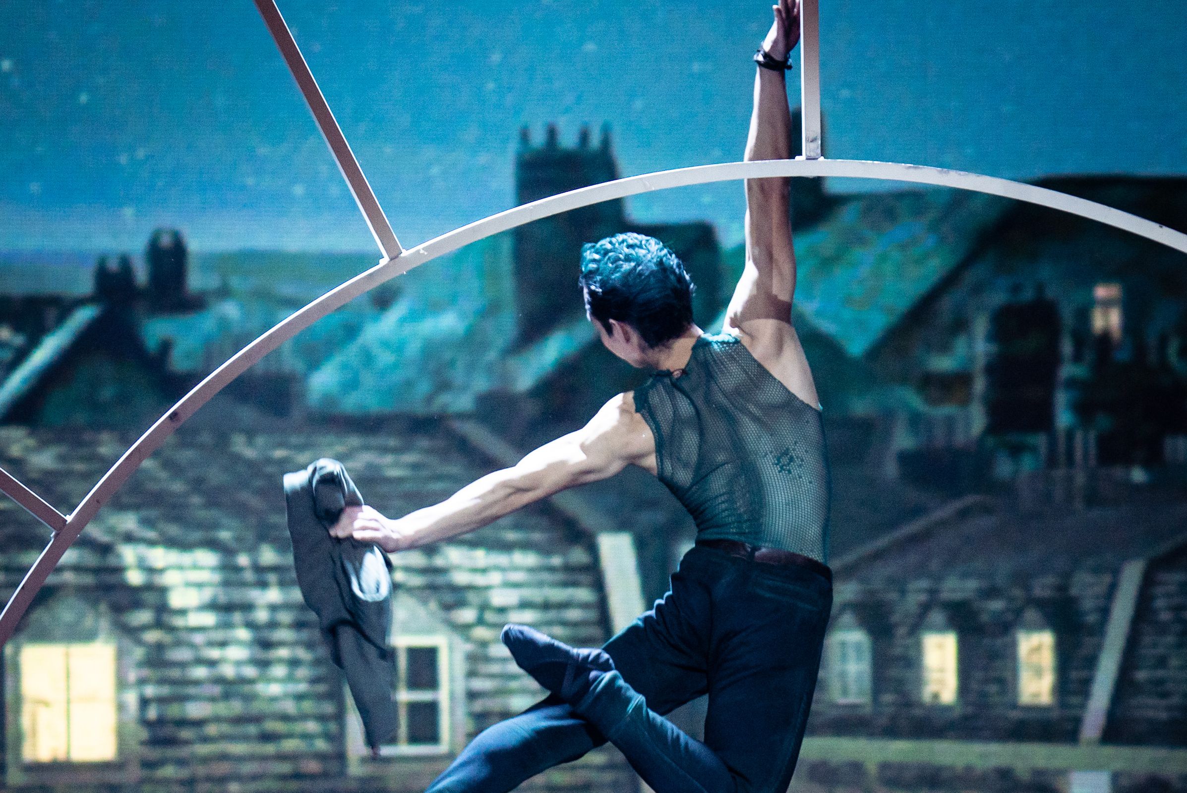 The subject of the ballet Peter Pan at the Volksoper Vienna shows a dancer from behind, floating as if through the air, against a backdrop of Wilhelminian-style buildings